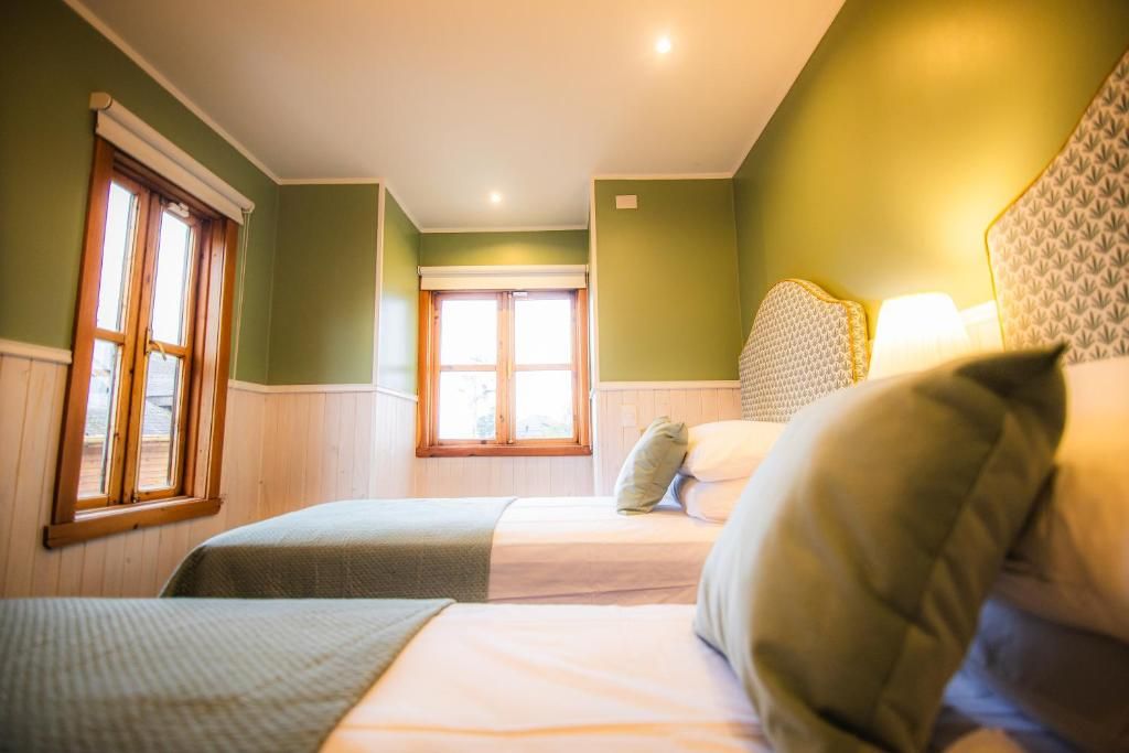 A room with two beds, a window, and a light fixture.