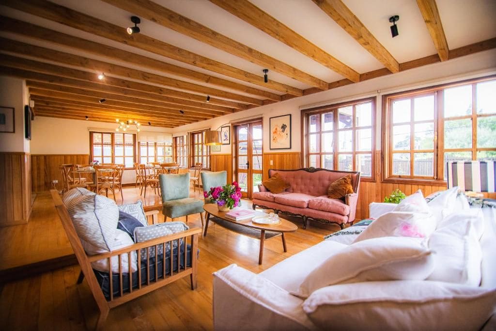 Un vaste espace de vie agrémenté de poutres en bois, comprenant un canapé, des fauteuils et une table basse.