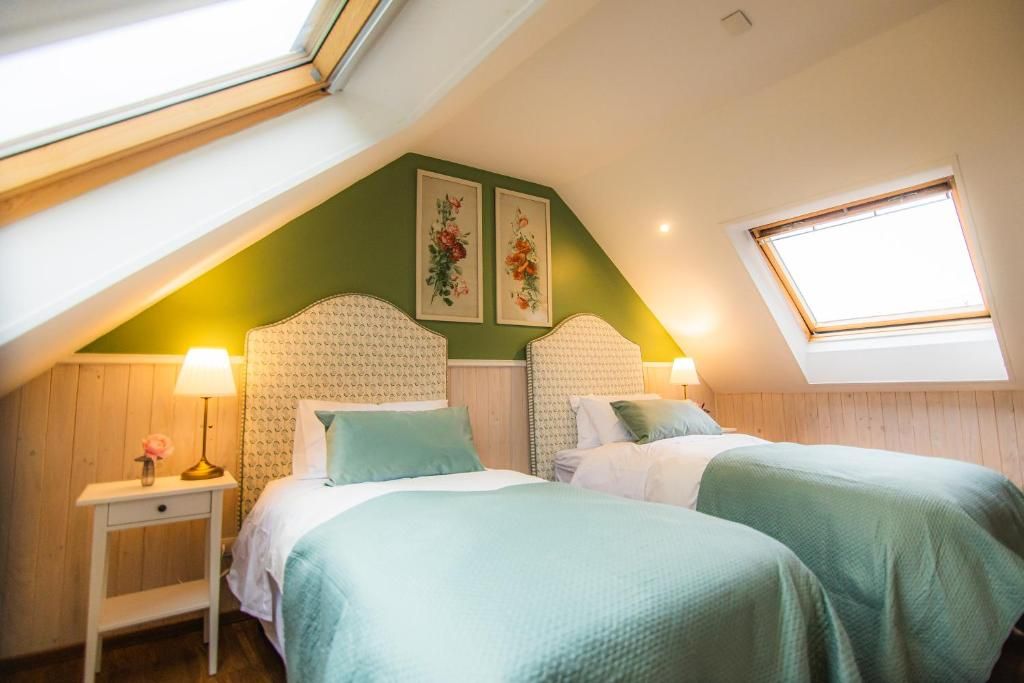 Une chambre avec deux lits, une lucarne et une fenêtre.