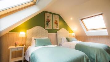 Une chambre avec deux lits, une lucarne et une fenêtre.