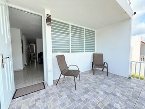 A balcony with two chairs, a door leading to an interior space, and a window with horizontal blinds. - NEW! Family Stay near Beaches, El Yunque, BioBay & Ferry (Fajardo)