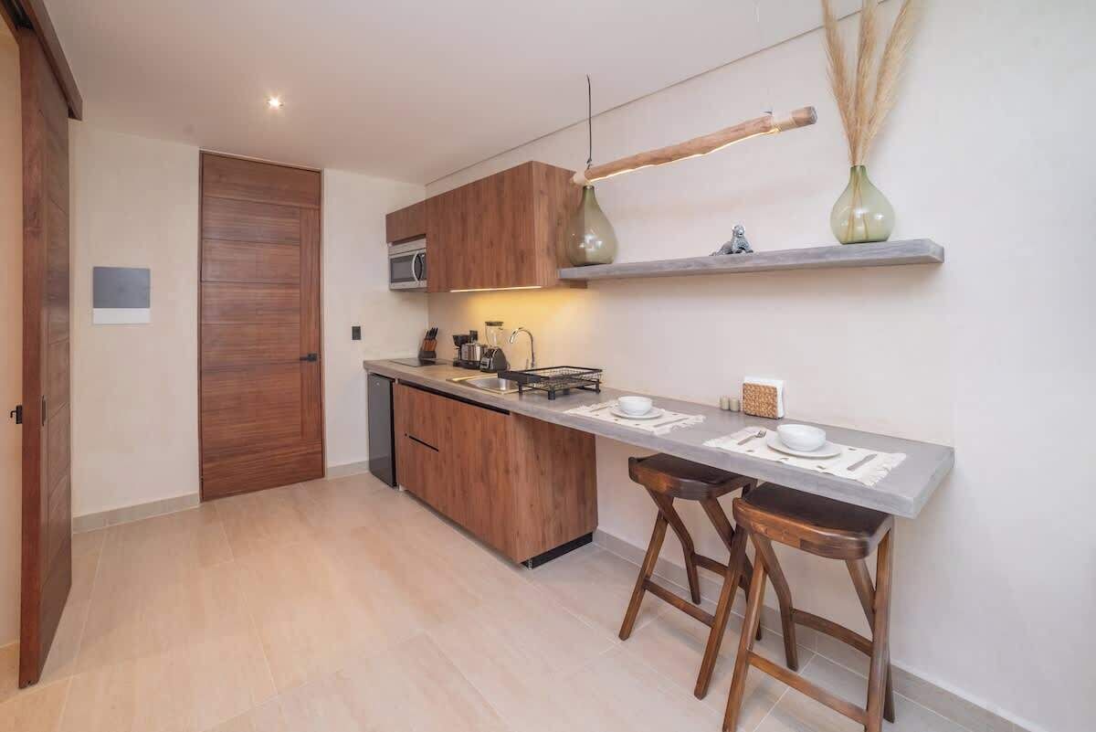 A modern kitchen with wooden cabinets, a built-in oven, a countertop with bar stools, and a hanging pendant light.
