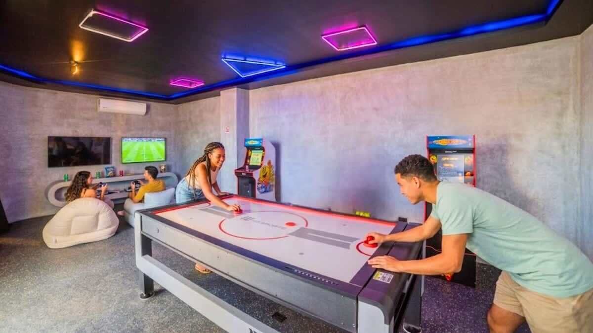 Una habitación con mesa de futbolín, juegos de arcade y una pantalla de televisión.
