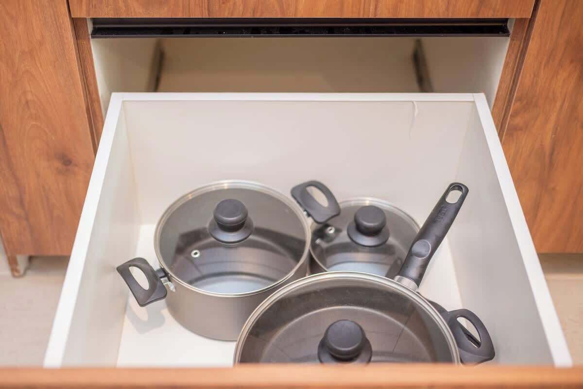 A drawer with three pots and a pan.