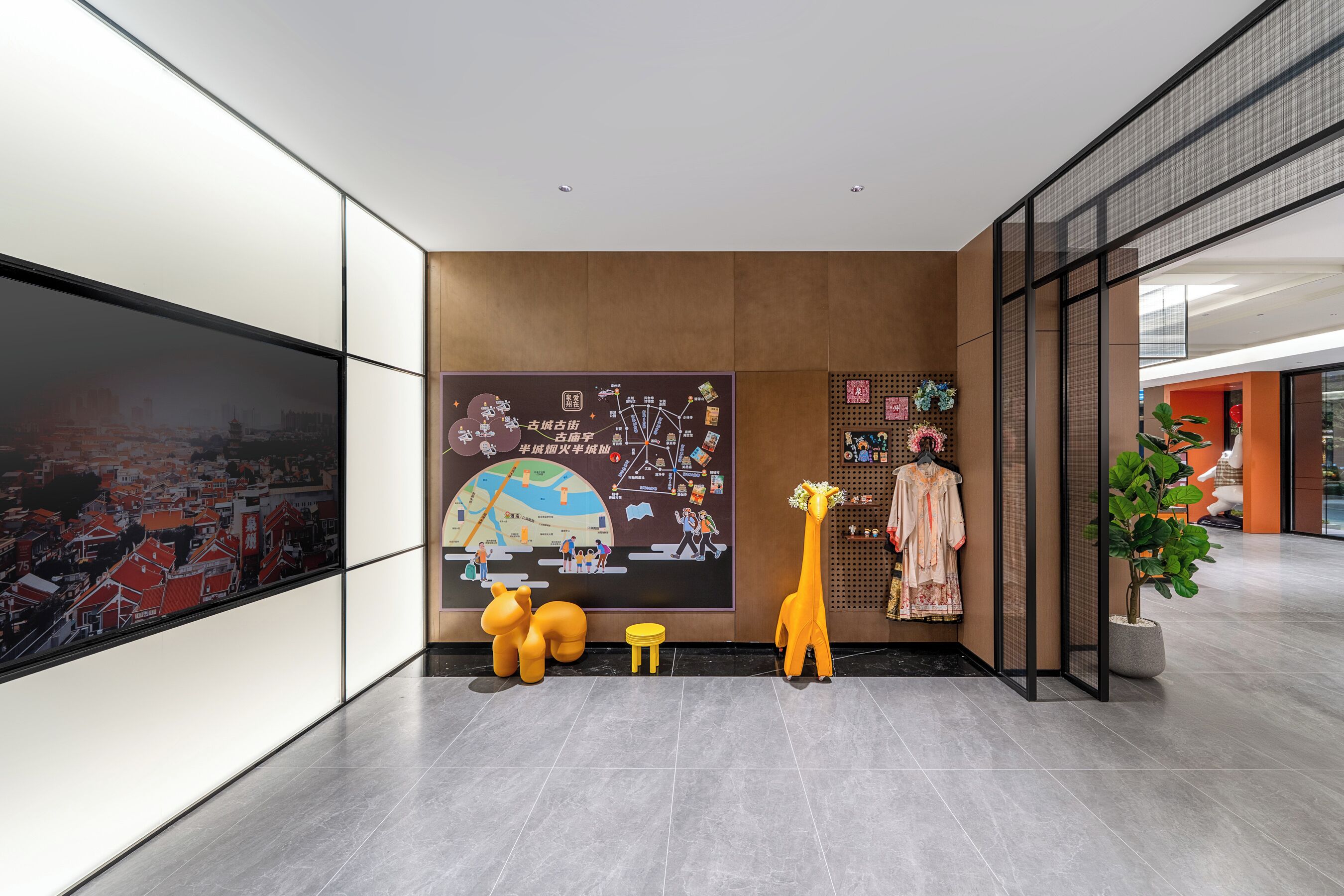 A modern lobby with a large map mural, a giraffe statue, a small stool, and a potted plant.