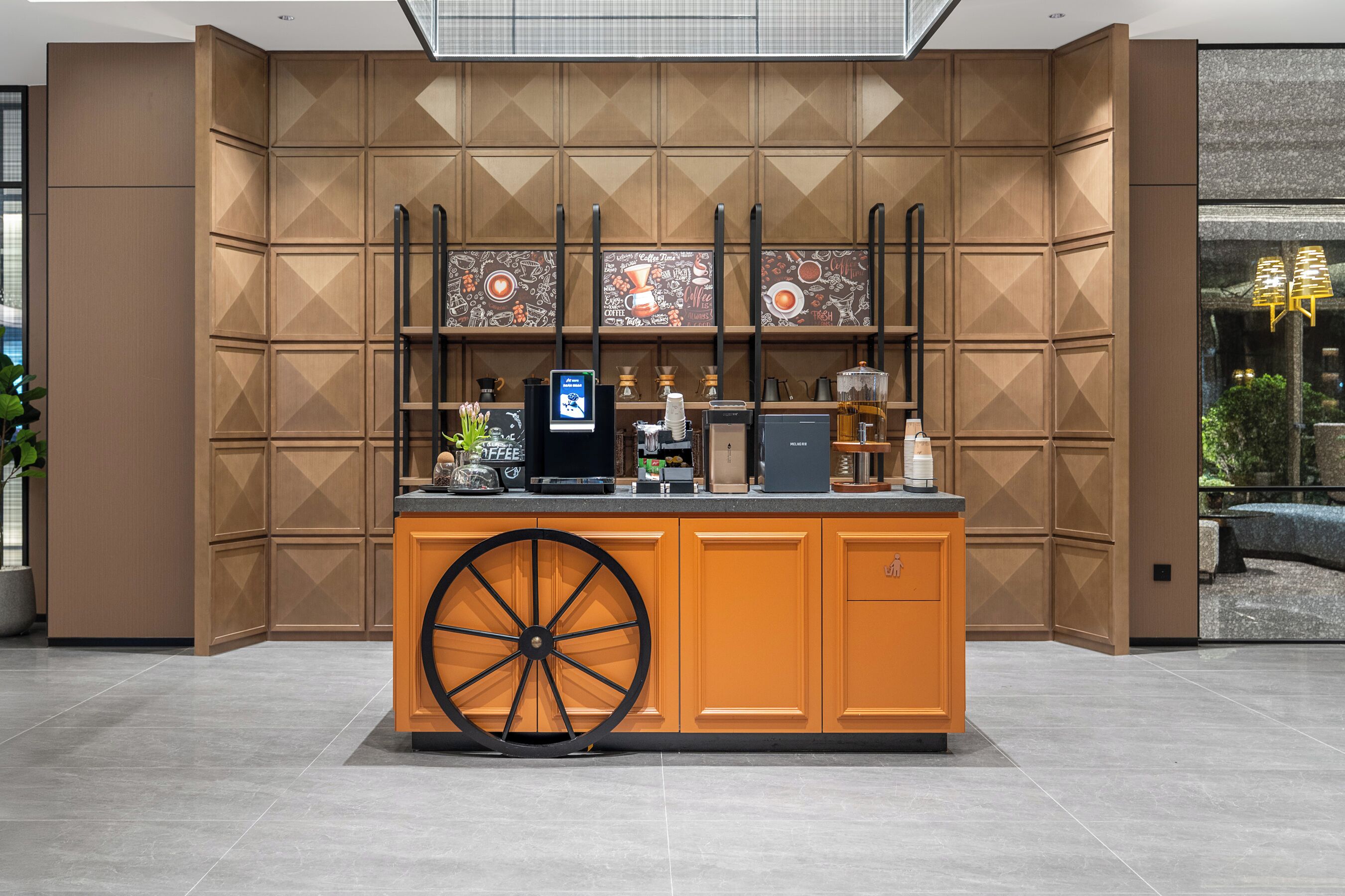 A modern coffee bar with a large wheel, a coffee machine, and a digital screen.