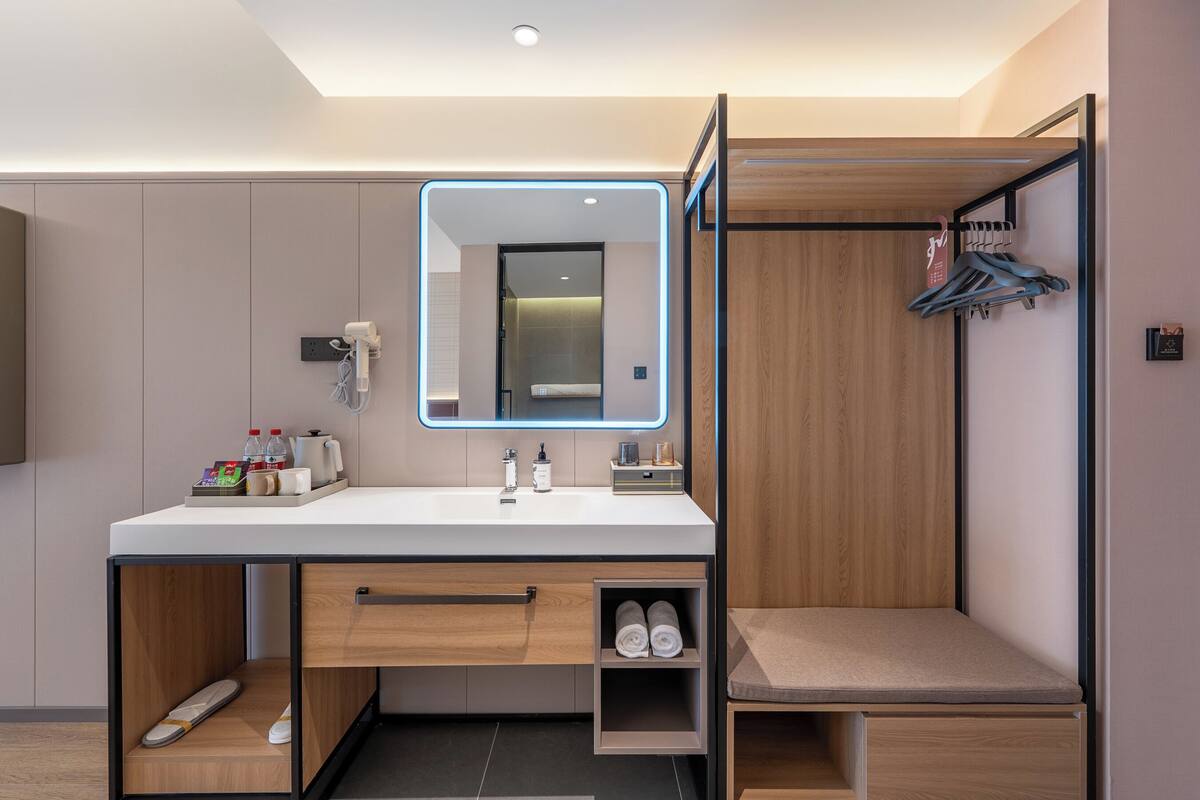 A modern bathroom with a vanity, mirror, towel storage, and a shower area.