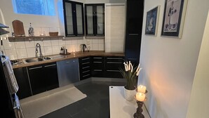Eine moderne Küche mit schwarzen Schränken, einer Holz Arbeitsplatte, einem Spülbecken, einem Fenster und einem kleinen Tisch mit Kerzen.