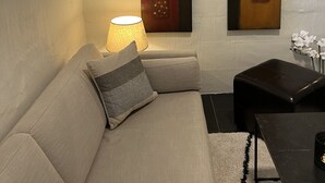Ein modernes Wohnzimmer mit einer Couch, einer Lampe und zwei Bildern an der Wand.