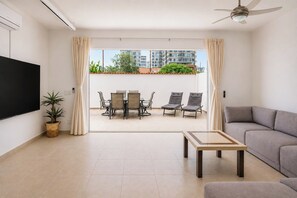 Ein modernes Wohnzimmer mit Flachbildfernseher, einer Couch, einem Couchtisch und einem Balkon mit Tisch und Stühlen.