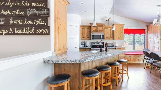 A kitchen with wooden cabinets, a granite countertop, and bar stools.