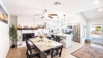 A modern kitchen with white cabinets, a central island, and a dining area with a wooden table and chairs.