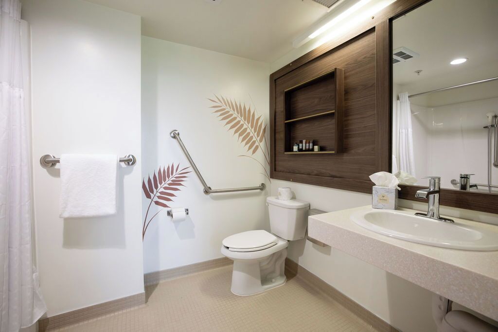 A bathroom with a toilet, sink, and mirror.