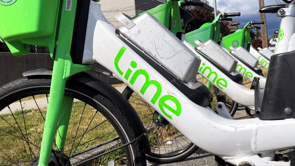 A row of Lime electric scooters parked on a concrete surface.