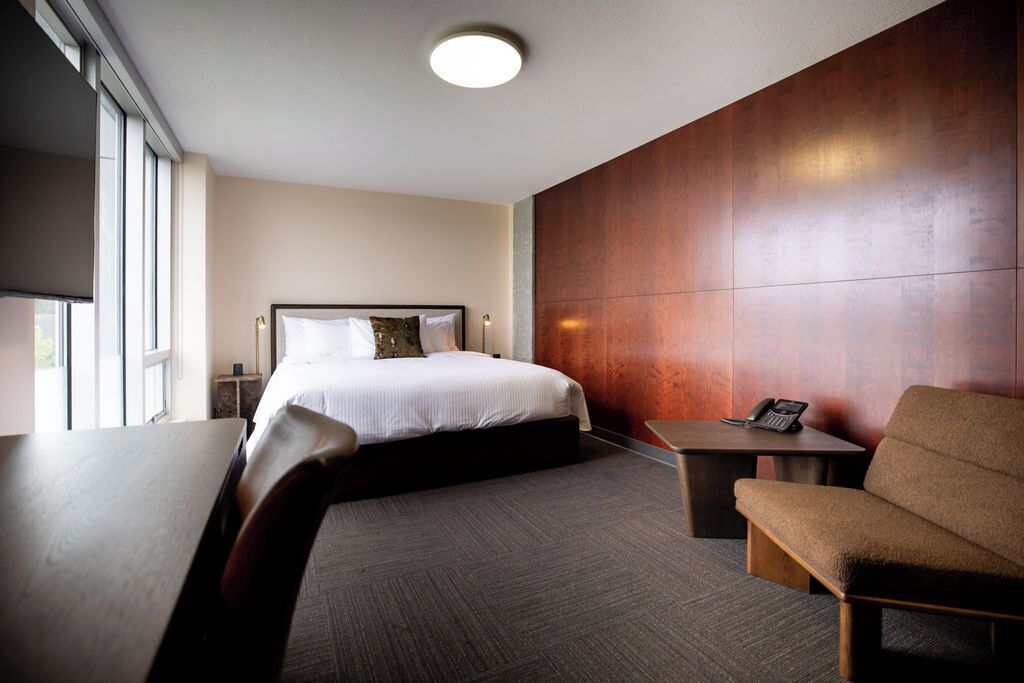 Une chambre d’hôtel comprenant un lit, un bureau, une chaise et une table de chevet.