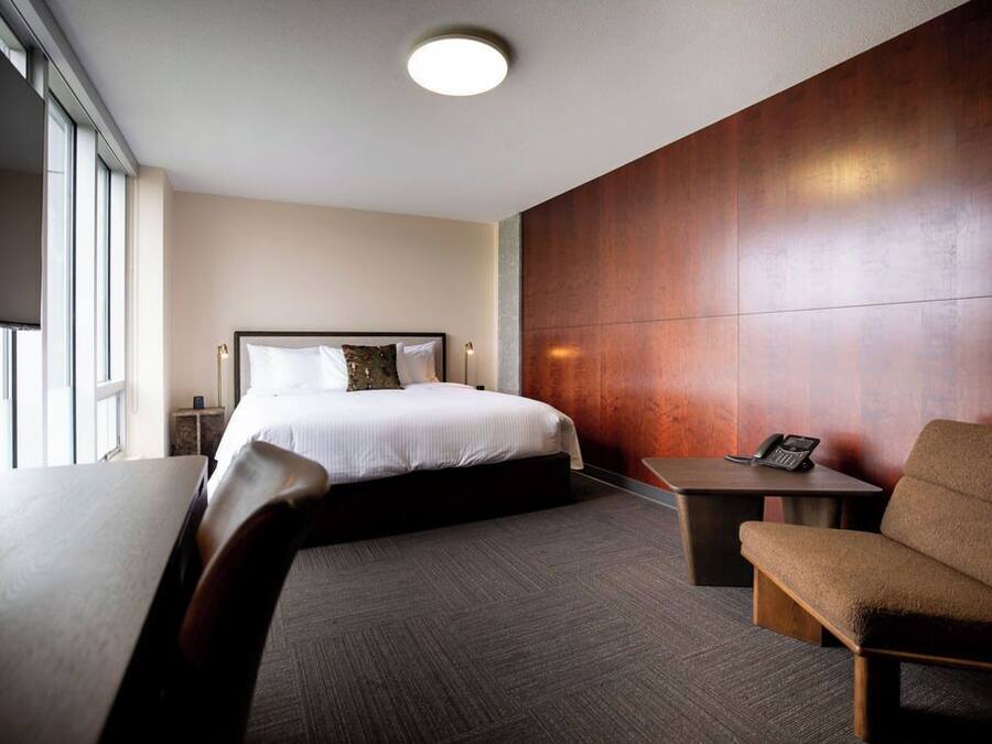 Une chambre d’hôtel comprenant un lit, un bureau, une chaise et une table de chevet.