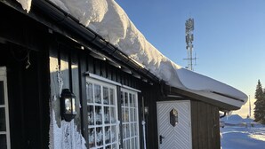 A snow-covered building with a wooden exterior, large windows, and a door. - Mountain cabin in Lillehammer (Lillehammer)