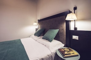 A bed with a headboard, two pillows, a bedside table with a book, and a wall-mounted lamp. - Dolcevita Panisperna 6 Gina Loft Apartment (Rome)