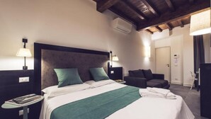 A hotel room with a bed, bedside tables, a reading lamp, a chair, and a wardrobe. - Dolcevita Panisperna 6 Gina Loft Apartment (Rome)