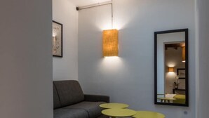A modern room with a skylight, a sofa, a small table, and a mirror. - Dolcevita Panisperna 1 Norma Apartment (Rome)