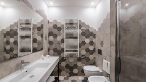 A modern bathroom with a large mirror, a dual sink vanity, a toilet, and a shower area. - Dolcevita Panisperna 1 Norma Apartment (Rome)
