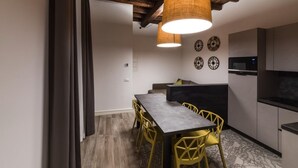 A modern kitchen with a dining area, wooden ceiling beams, and a microwave. - Dolcevita Panisperna 1 Norma Apartment (Rome)