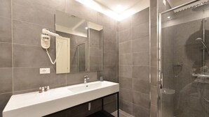 A modern bathroom with a large sink, a mirror, a hairdryer, and a shower area. - Dolcevita Panisperna 5 Audrey Ground Floor Apartment (Rome)