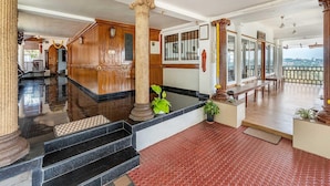 Un vestíbulo espacioso con una escalera de mármol, paneles de madera y un balcón con vistas a la ciudad.