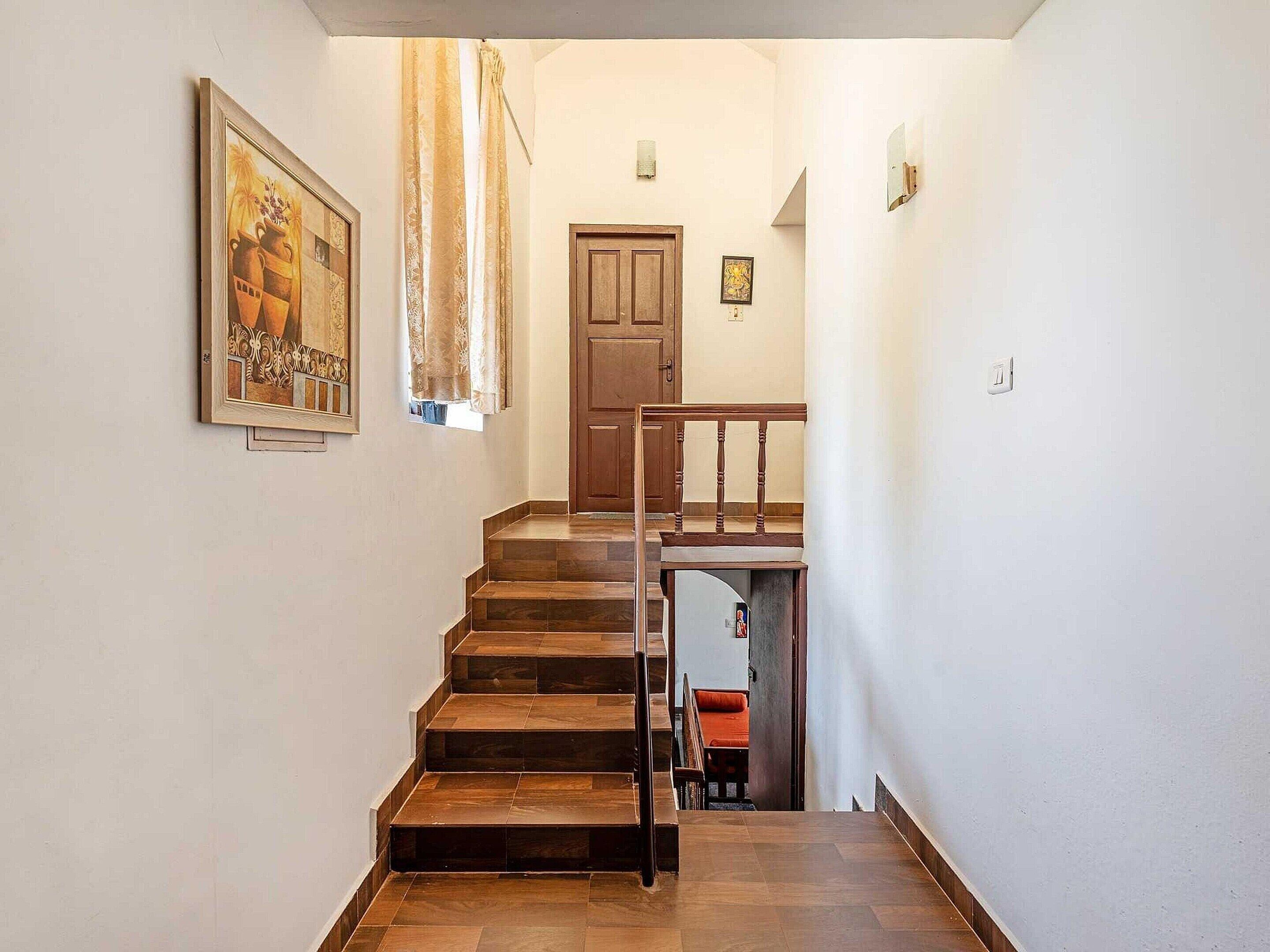 A staircase with wooden steps leading to a landing, a door, and a framed picture on the wall.