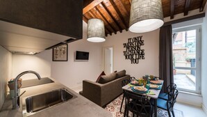 A modern kitchen with a built-in sink, a dining area with a table and chairs, and a living area with a sofa. - Dolcevita Panisperna 4 - Liz Apartment (Rome)