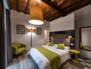 Ein Schlafzimmer mit einem Bett, einem grünen Sessel, einer Stehlampe, einem Nachttisch und einem Spiegel.
