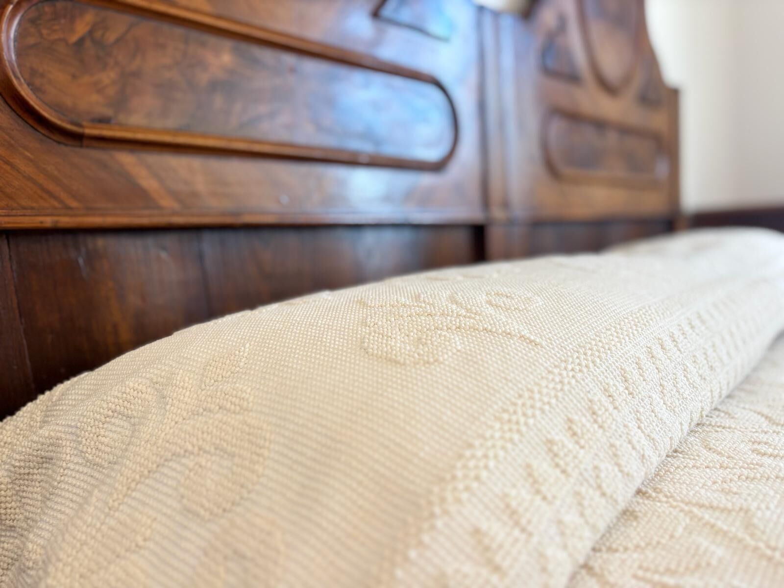 Primer plano de una cama con un colchón blanco texturizado y un cabecero de madera.