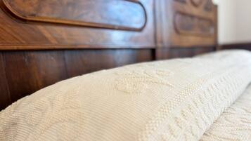 Primer plano de una cama con un colchón blanco texturizado y un cabecero de madera.