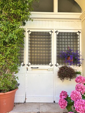 A white door with a number '233' and two windows with metal grilles. - Relais Casa Spanu (Dorgali)