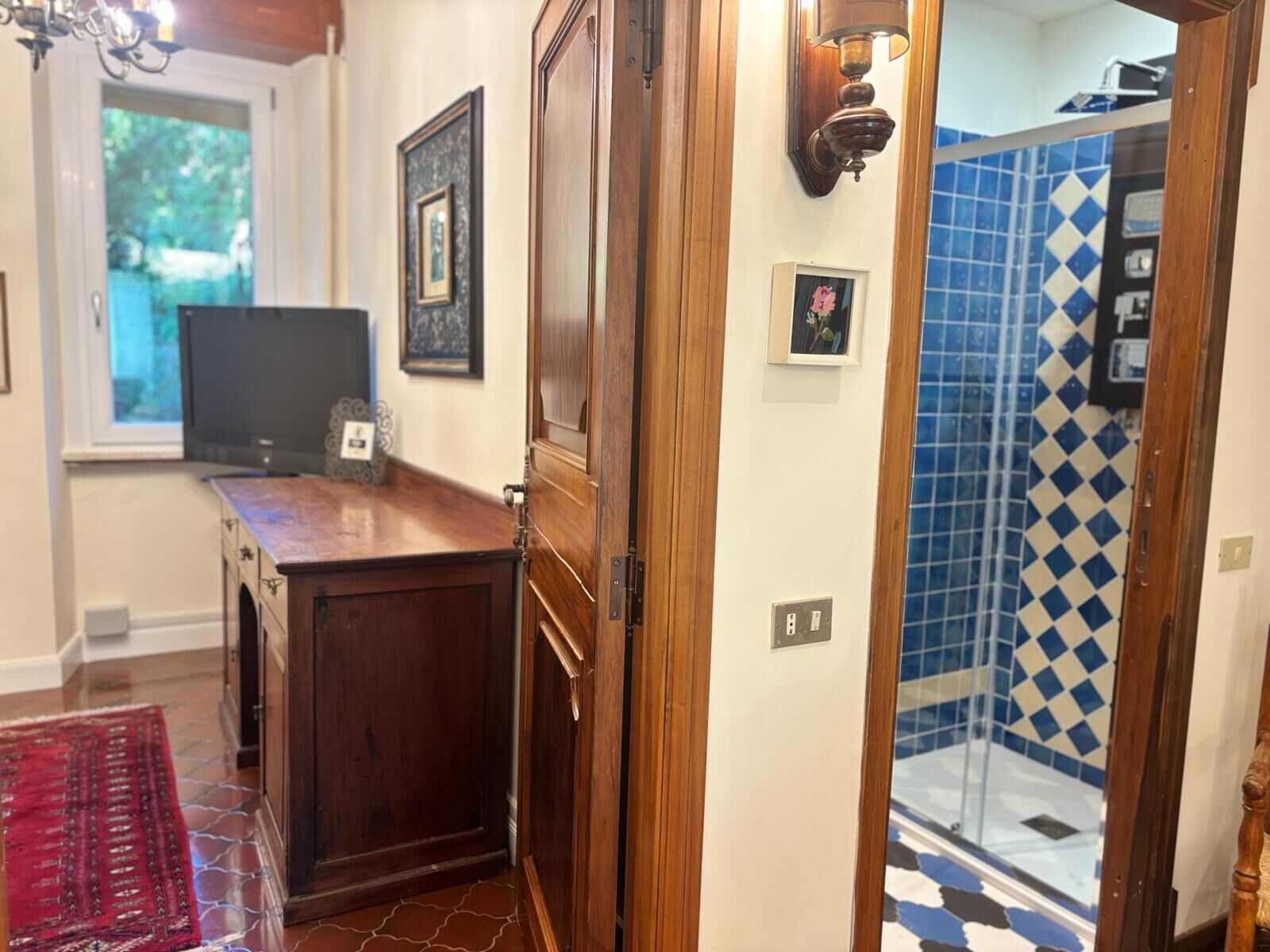 Un baño con ducha, puerta de madera y pared con azulejos.