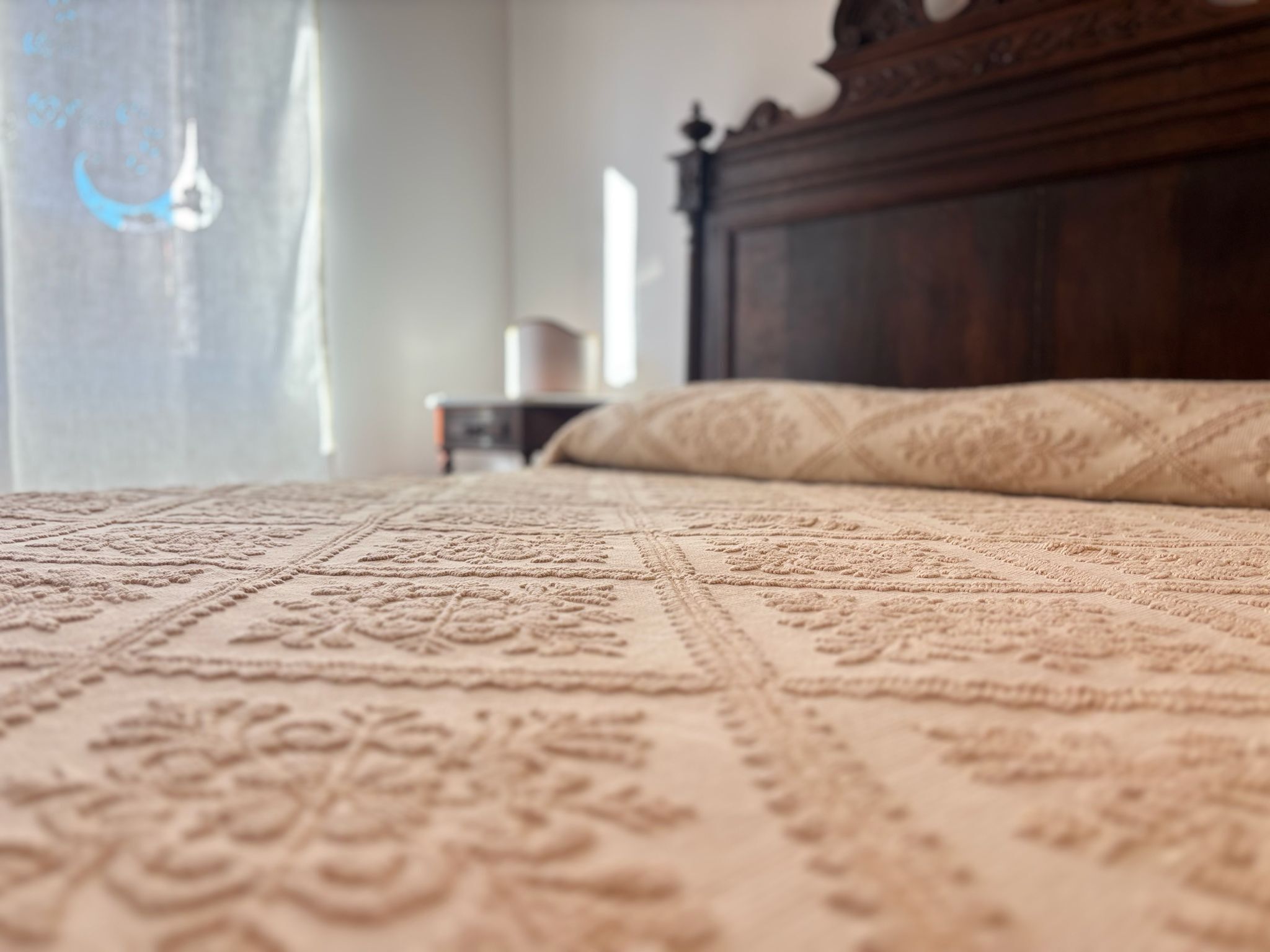 Um close-up de uma cama com colcha estampada e cabeceira de madeira.