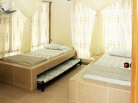 Dormitorio con dos camas, ventilador de techo y cortinas con un diseño circular.