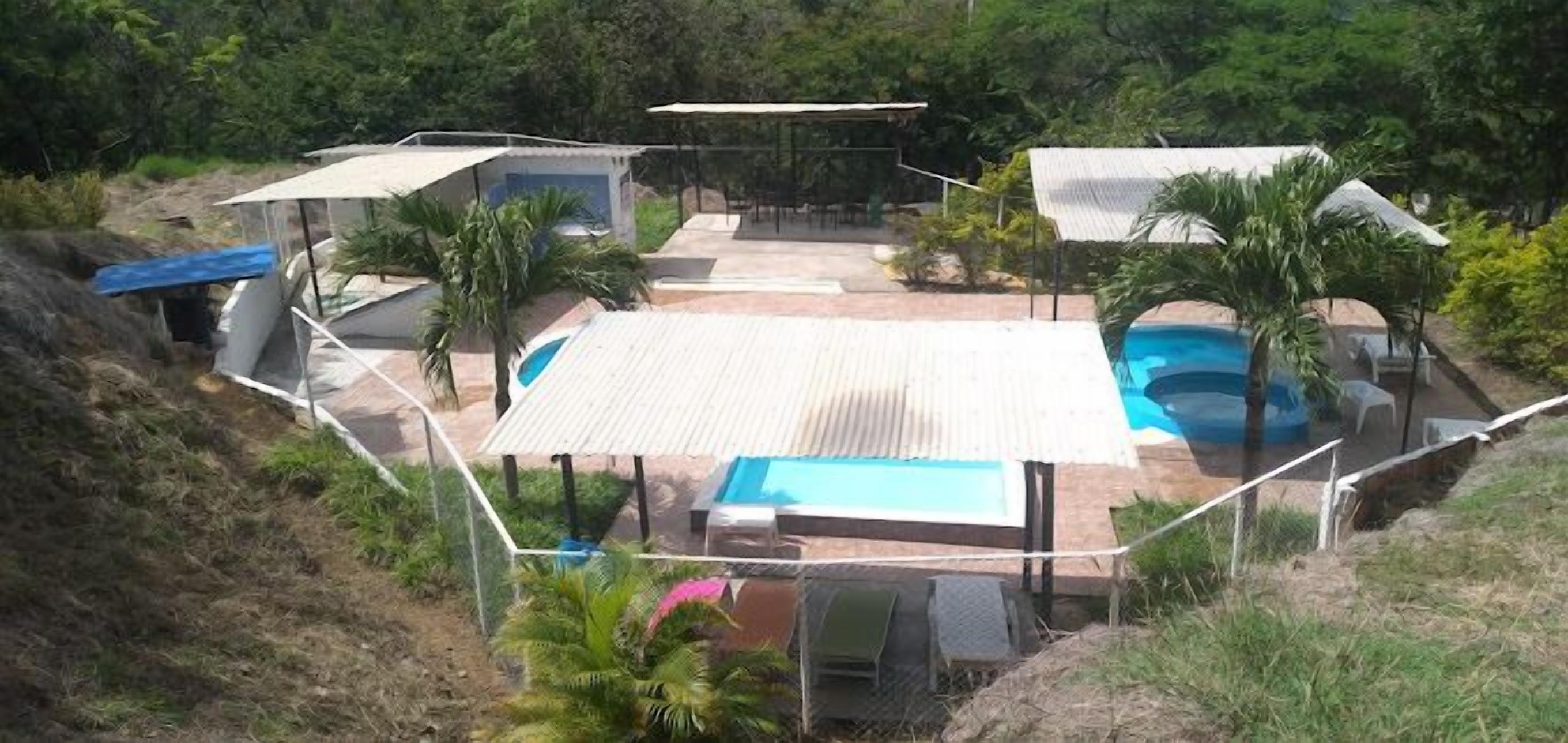Una proprietà residenziale con piscina, patio coperto e diverse zone relax all'aperto.