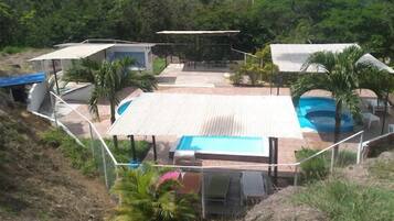 Una proprietà residenziale con piscina, patio coperto e diverse zone relax all'aperto.
