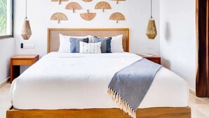 A neatly arranged bedroom with a large bed, a wooden headboard, bedside tables, and wall-mounted fans. - Casa Manglar - Golf Course Views, Near the Ocean (Puerto Aventuras)