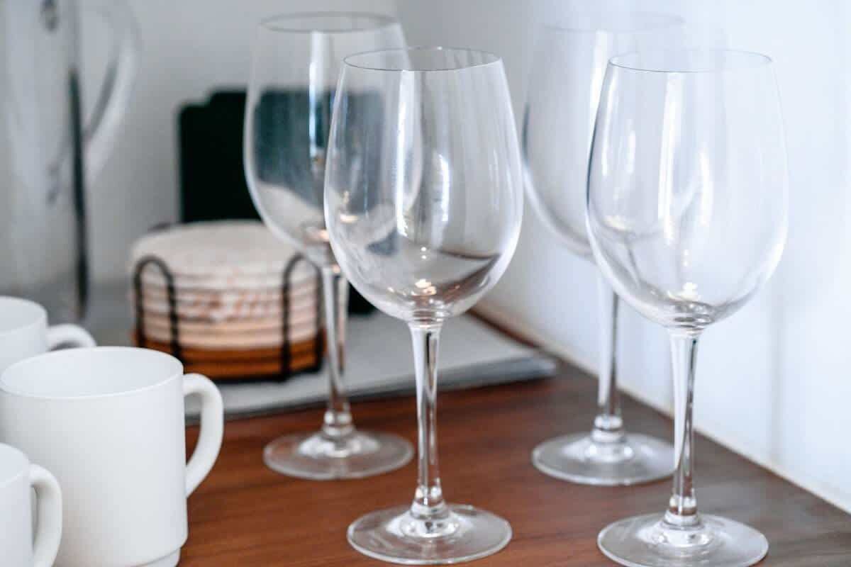 Une table avec des verres à vin en verre transparent et des tasses blanches.
