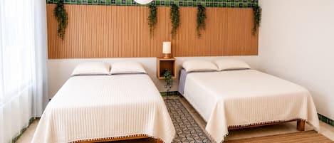 A room with two beds, a wooden headboard, a patterned rug, and a hanging plant.