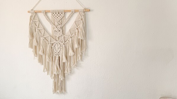 Un tapiz de macramé con marco de madera, con elaborados diseños de nudos y flecos.