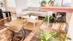 A living room with a sofa, coffee table, wicker chair, and a fireplace.