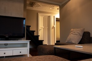 A living room with a television, a sofa, a table, and a staircase leading to another room. - Arctic Comfort 1, Tromsø (Tromsø)
