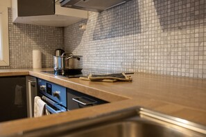 A kitchen with a tiled backsplash, stainless steel appliances, and a wooden countertop. - Arctic Comfort 1, Tromsø (Tromsø)