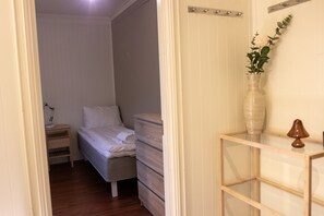 A bedroom with a bed, a dresser, a nightstand, a lamp, and a vase with flowers. - Arctic Comfort 1, Tromsø (Tromsø)