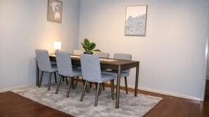 Een eetruimte met een tafel, stoelen, een plant en kunstwerken aan de wanden.