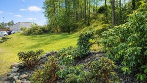 Een aangelegde tuin met een gazon, bomen en een gebouw op de achtergrond.
