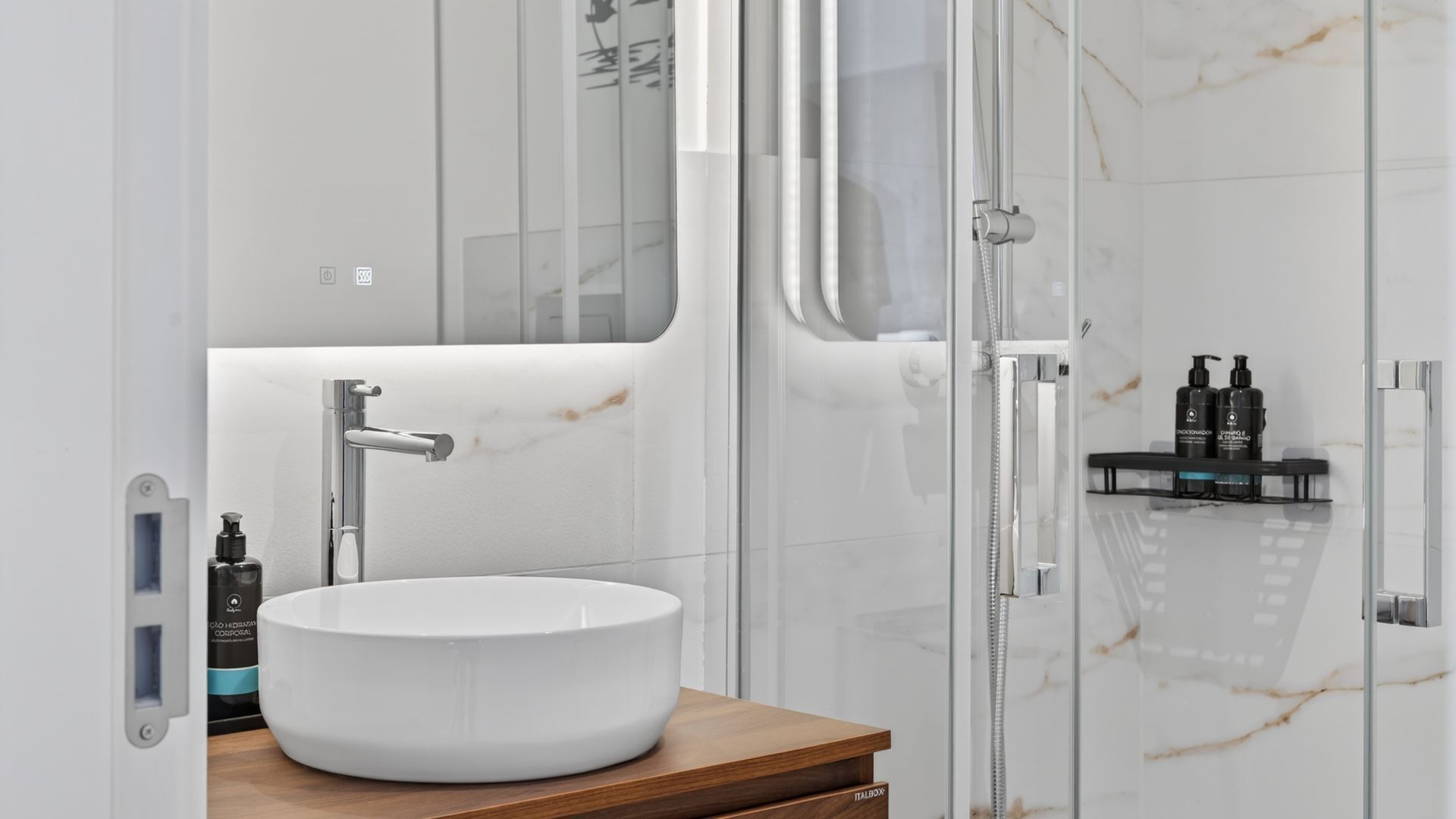 Een moderne badkamer met een rond wit wastafel, een chromen kraan en een glazen douchecabine.